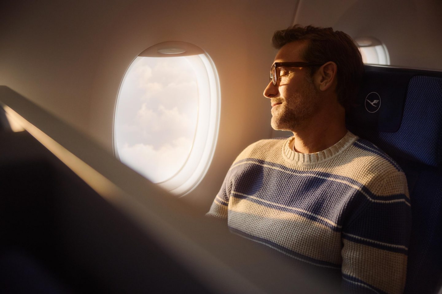 Ein Mann sitzt relaxed in der Premium Economy Class // A man sits relaxed in Premium Economy Class