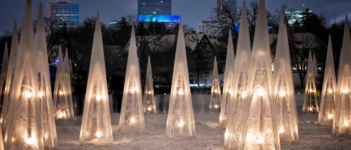 Illuminated ice sculptures on a snow-covered surface at night.