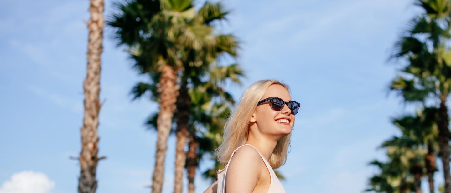 Blonde woman with sunglasses with palm trees in the background