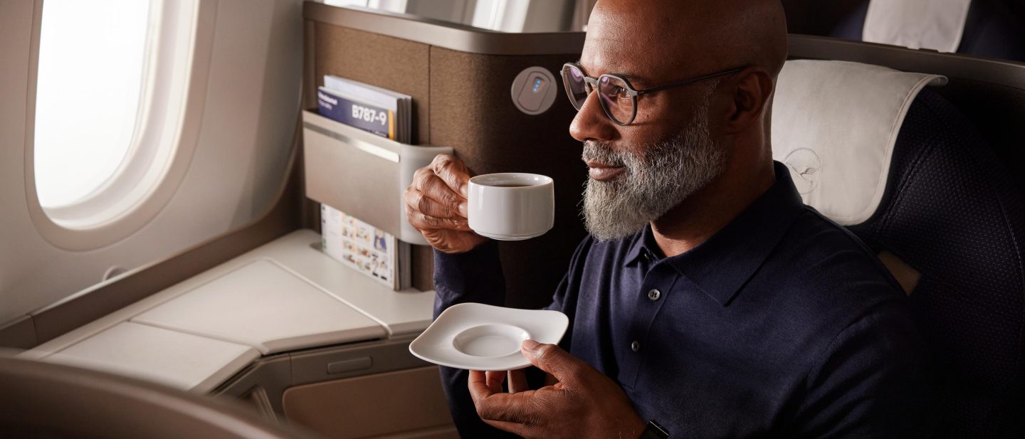 Mann mittleren Alters mit Bart und Brille trinkt Tee an Bord und sieht aus dem Fenster. // Middle-aged man with beard and glasses drinking tea on board and looking out the window. 