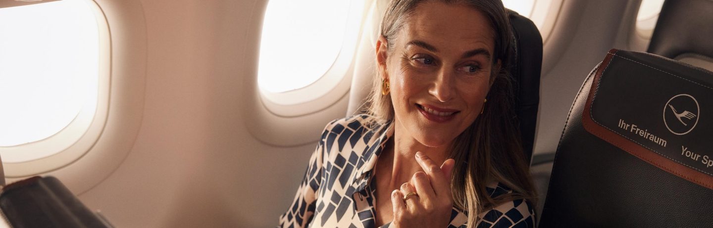 Eine Frau sitzt in der Business Class der A320neo und schaut entspannt aus dem Fenster. // A woman sits in Business Class on the A320neo and looks out of the window, relaxed.