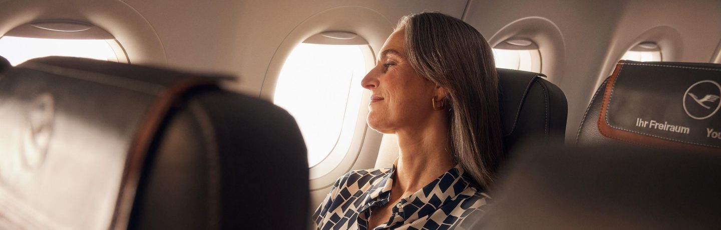 Eine Frau sitzt in der Business Class der A320neo und schaut entspannt aus dem Fenster. // A woman sits in Business Class on the A320neo and looks out of the window, relaxed.