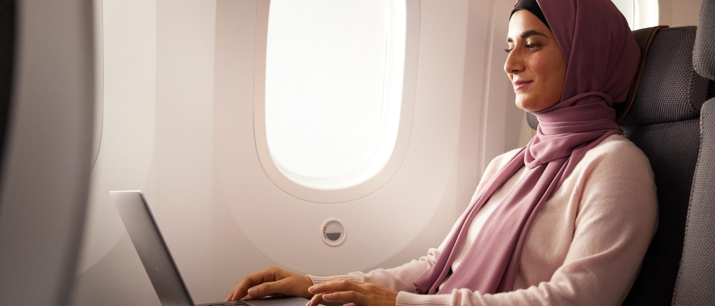 Junge Frau mit Hijab benutzt Laptop an Bord. // Young woman wearing hijab is using laptop on board. 