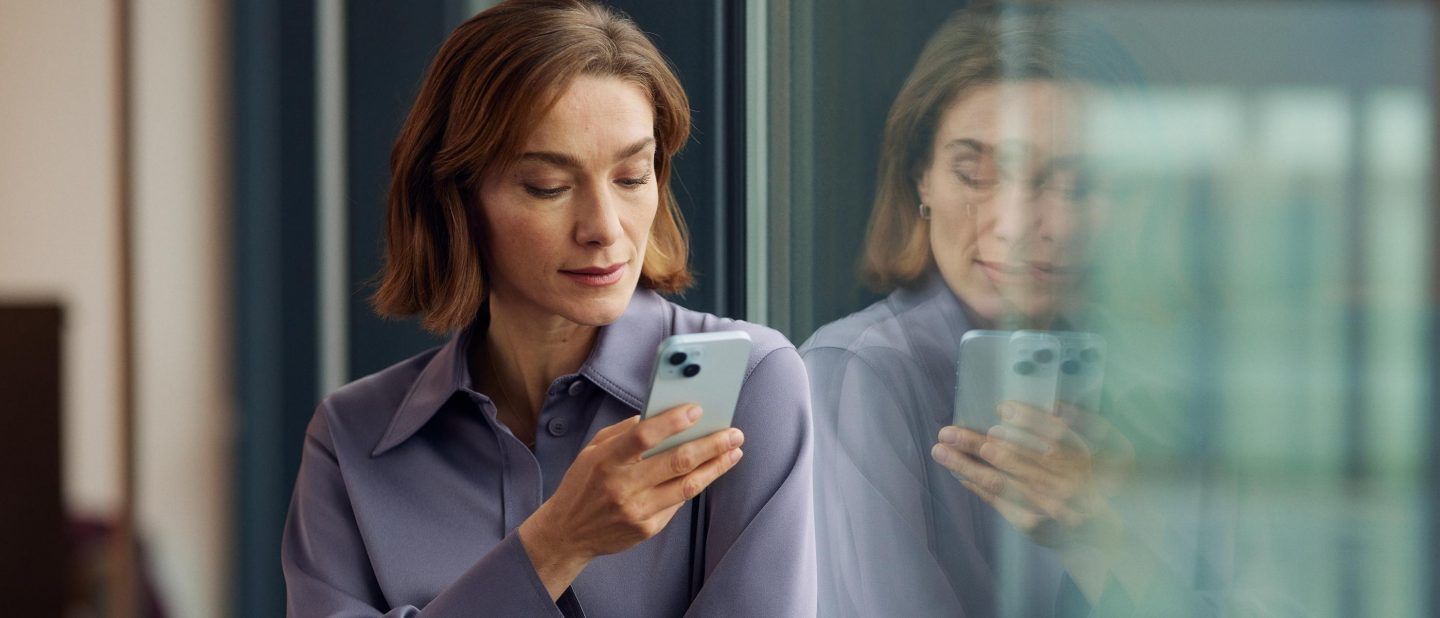 Eine Frau steht in der Lounge am Fenster und telefoniert. // A woman is standing by the window in the lounge talking on the phone.