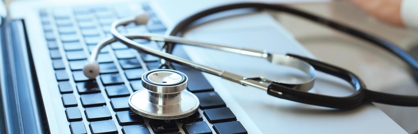 Stethoskop und Laptop auf einem Schreibtisch // Stethoscope and laptop on a desk